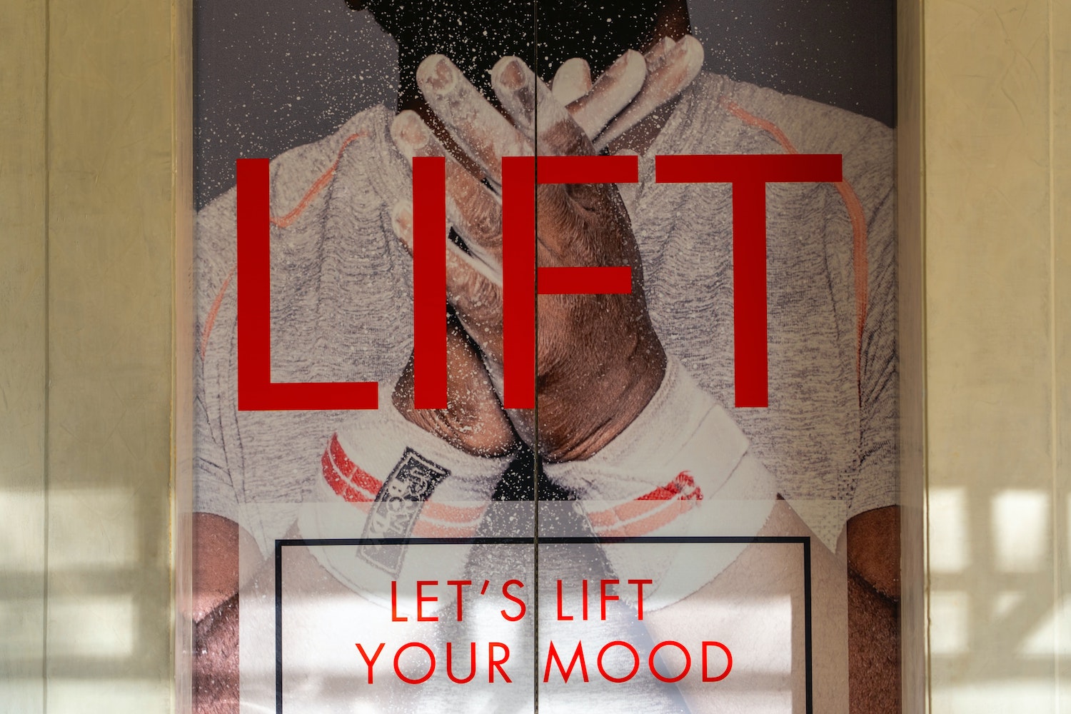 Elevator door with a poster of a man with text saying "Lift - let's lift your mood"